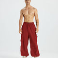 Bare-chested man in red baggy sweatpants, white shoes, highlighting waist and length details.