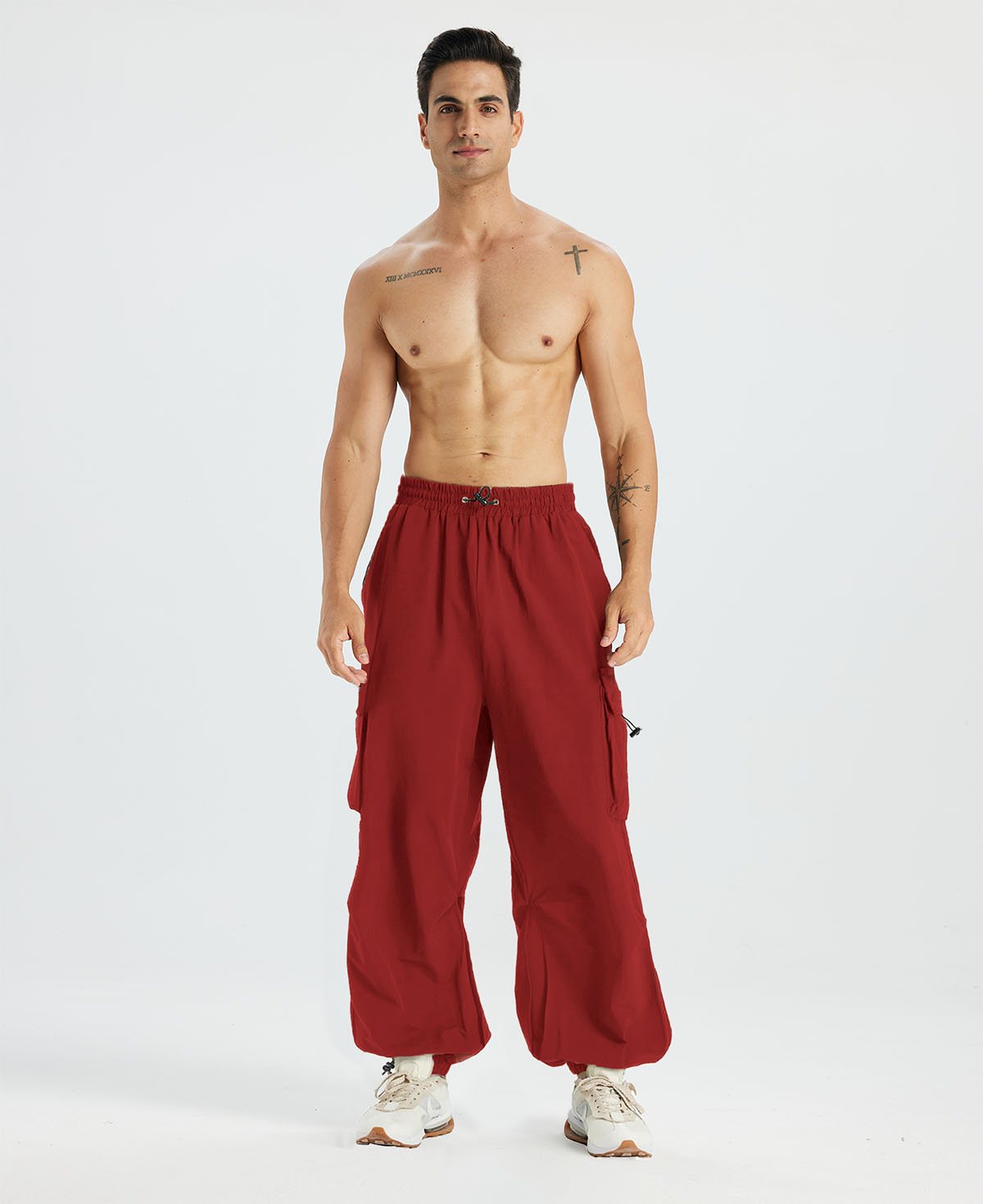 Bare-chested man in red baggy sweatpants, white shoes, highlighting waist and length details.
