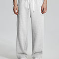 Model in white Men's Fleece Sweatpants ¨C Wide Leg Heavyweight Lounge Pants with white sneakers, showing drape and relaxed fit.