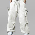 Man in white baggy sweatpants, high waist, five pockets, back logo. White sneakers, standing front.