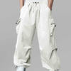 Man in white baggy sweatpants, high waist, five pockets, back logo. White sneakers, standing front.