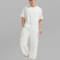 Full view of man wearing white baggy sweatpants with white tee and sneakers, highlighting fit.