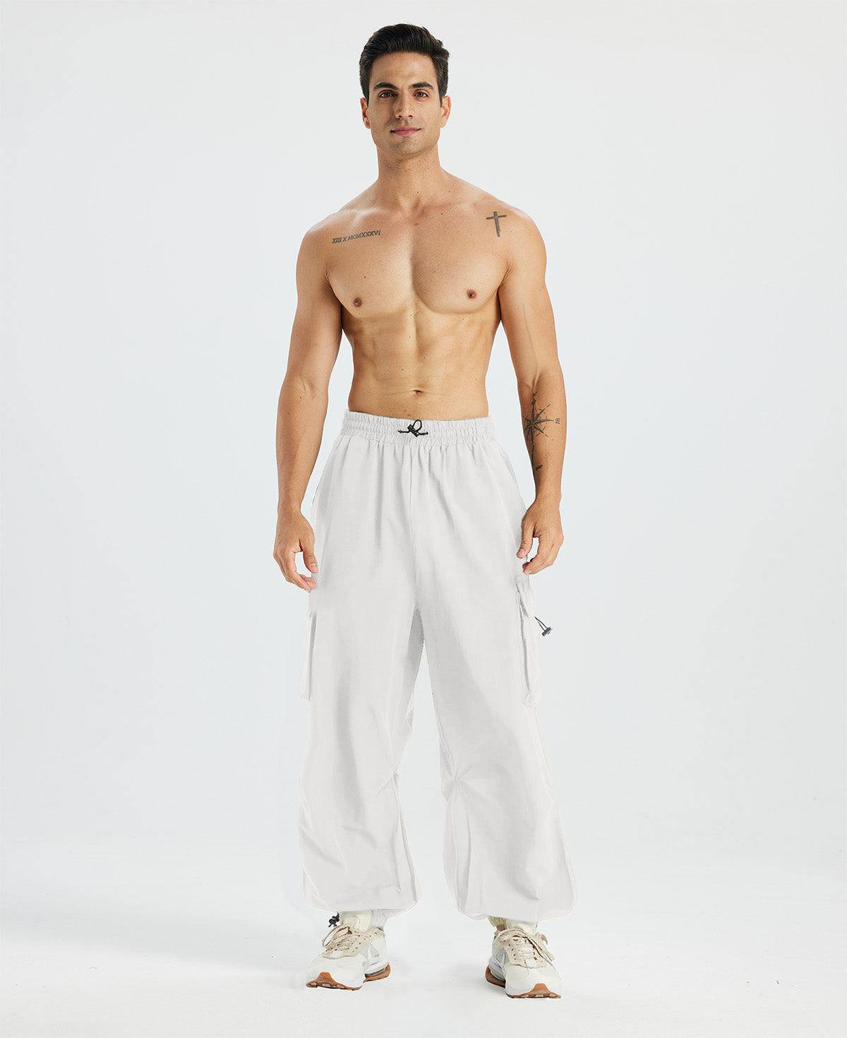 Bare-chested man in white baggy sweatpants, white shoes, highlighting waist and length details.