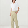 Model in white tee paired with dark khaki Men's Pleated Baggy Dress Pants showing fresh casual style.