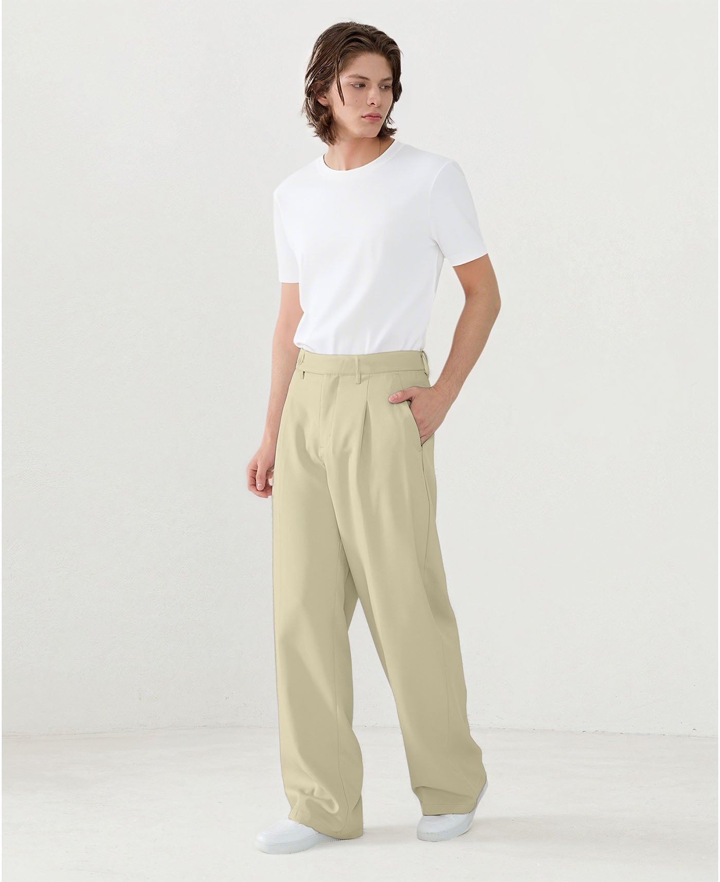 Model in white tee paired with dark khaki Men's Pleated Baggy Dress Pants showing fresh casual style.