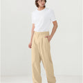 Model in white tee paired with light khaki Men's Pleated Baggy Dress Pants showing fresh casual style.