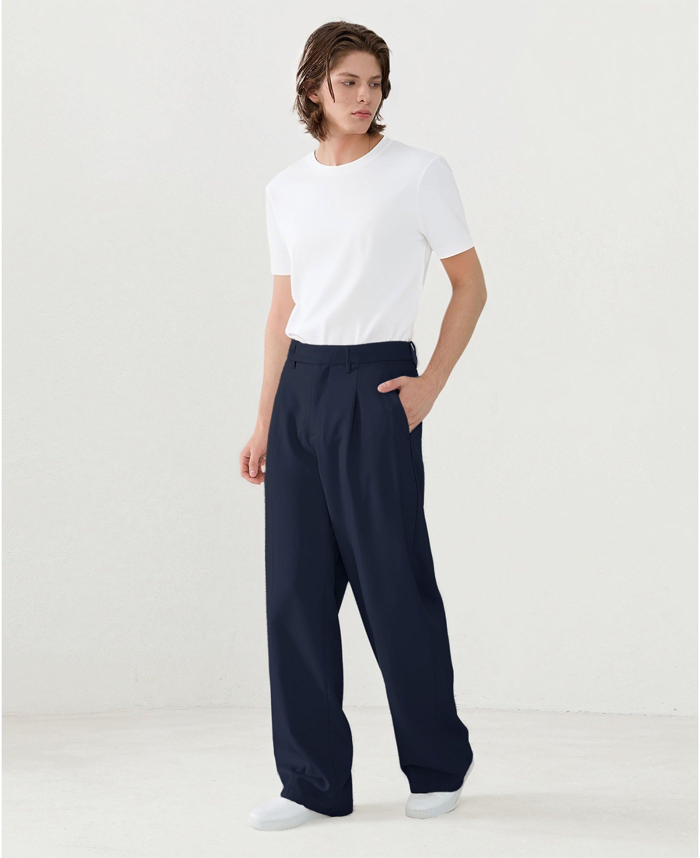 Model in white tee paired with navy blue Men's Pleated Baggy Dress Pants showing fresh casual style.