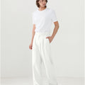 Model in white tee paired with white Men's Pleated Baggy Dress Pants showing fresh casual style.