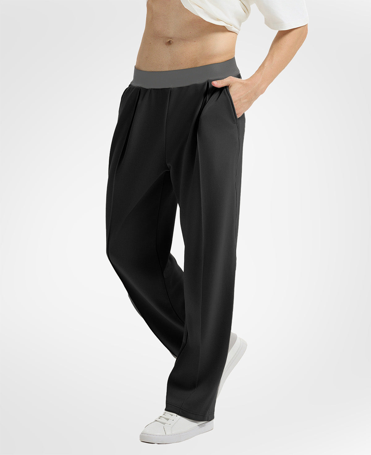 Side view of black wide-leg sweatpants showing front pleats and drape, hand in pocket highlighting pocket design.