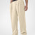Man in khaki pleated baggy sweatpants with white shoes, hand in pocket, showcasing wide leg and contrasting elastic waist.