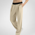 Side view of khaki wide-leg sweatpants showing front pleats and drape, hand in pocket highlighting pocket design.