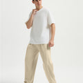 Man in white tee and khaki wide-leg sweatpants standing naturally, showcasing simple everyday style.