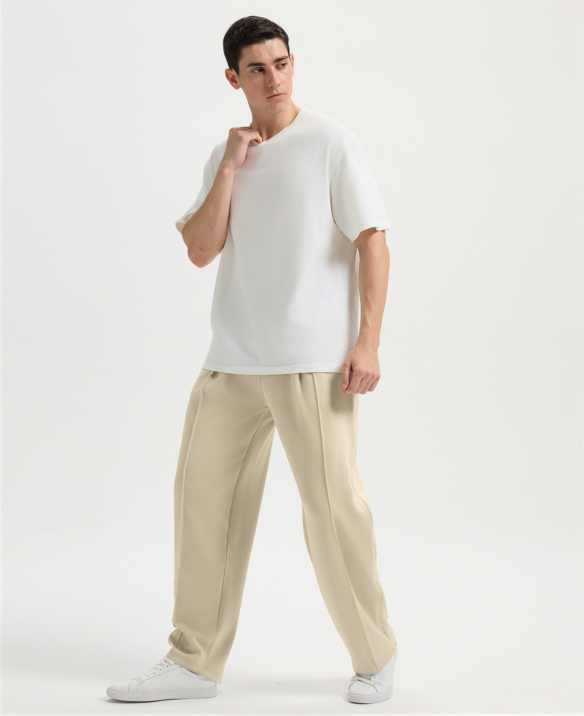 Man in white tee and khaki wide-leg sweatpants standing naturally, showcasing simple everyday style.