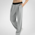 Side view of light grey wide-leg sweatpants showing front pleats and drape, hand in pocket highlighting pocket design.