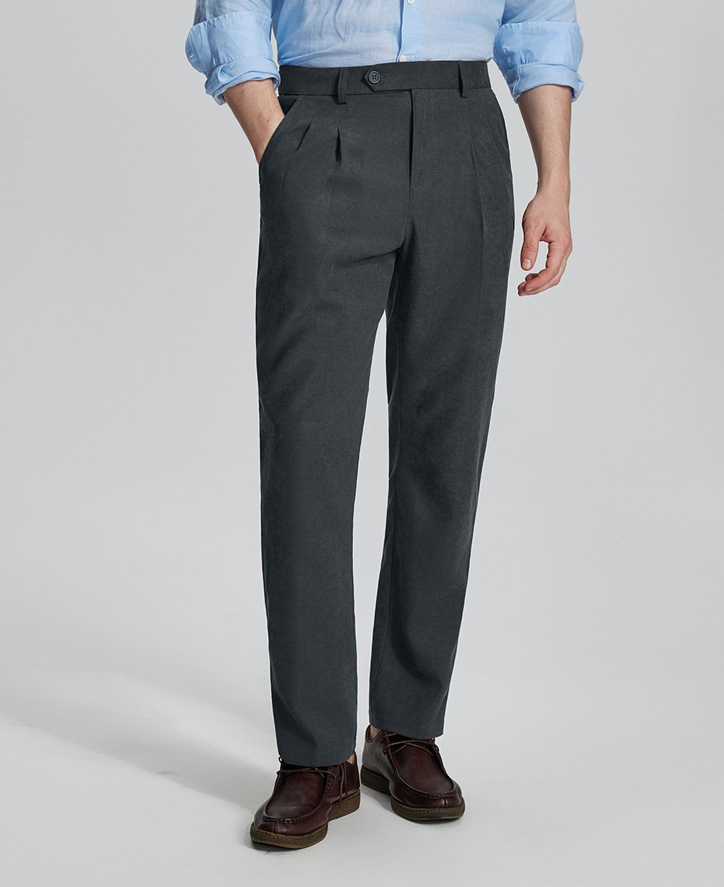 Man in light blue shirt, grey Mens Pleated Dress Pants, and brown shoes showcasing regular fit & straight-leg style.