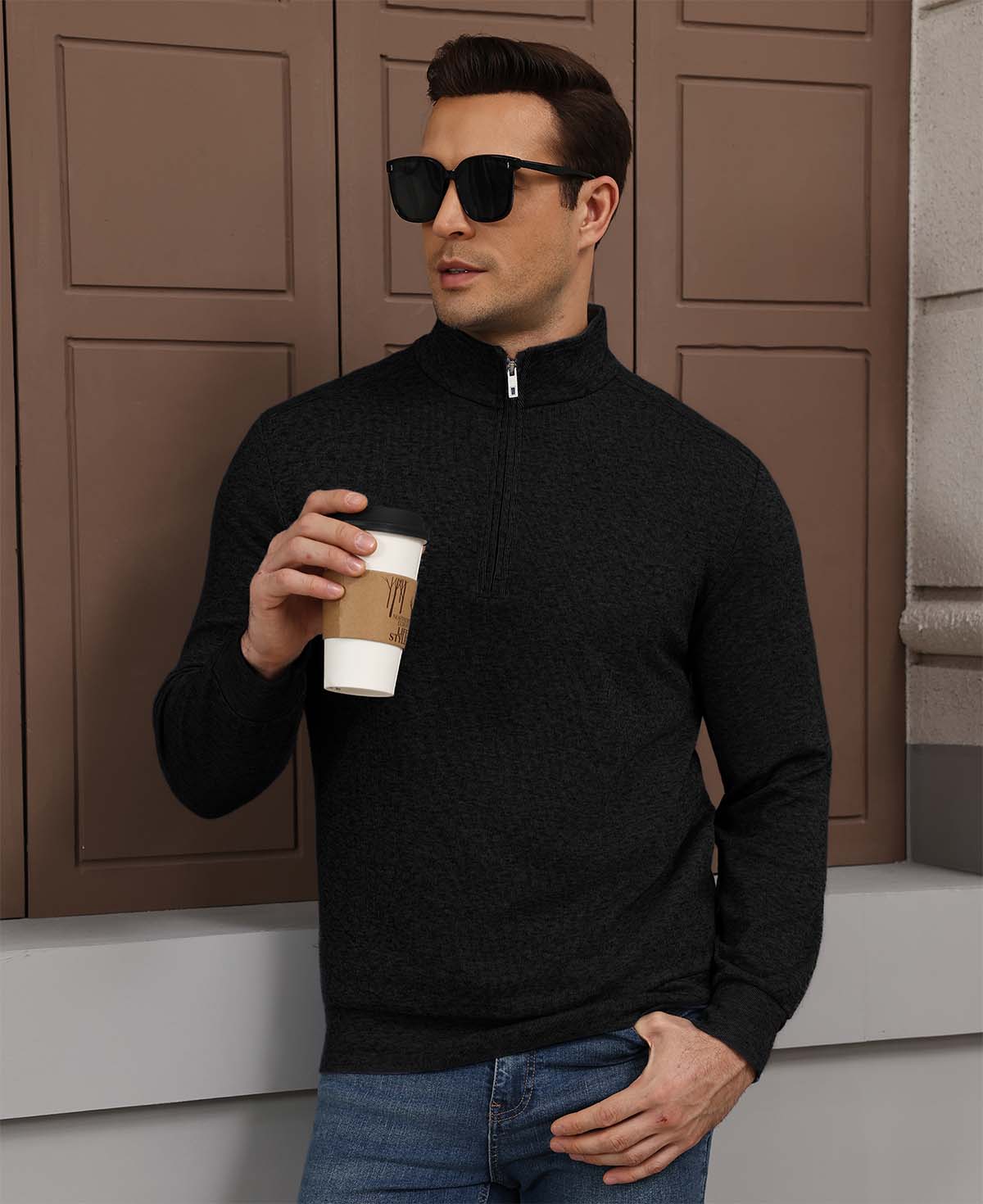 Model holding coffee in black Men's Quarter Zip Sweater, comfortable look for light casual settings.