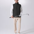 Model wearing black Men's Softshell Vest with golf club, ideal lightweight layer for outdoor leisure activities.