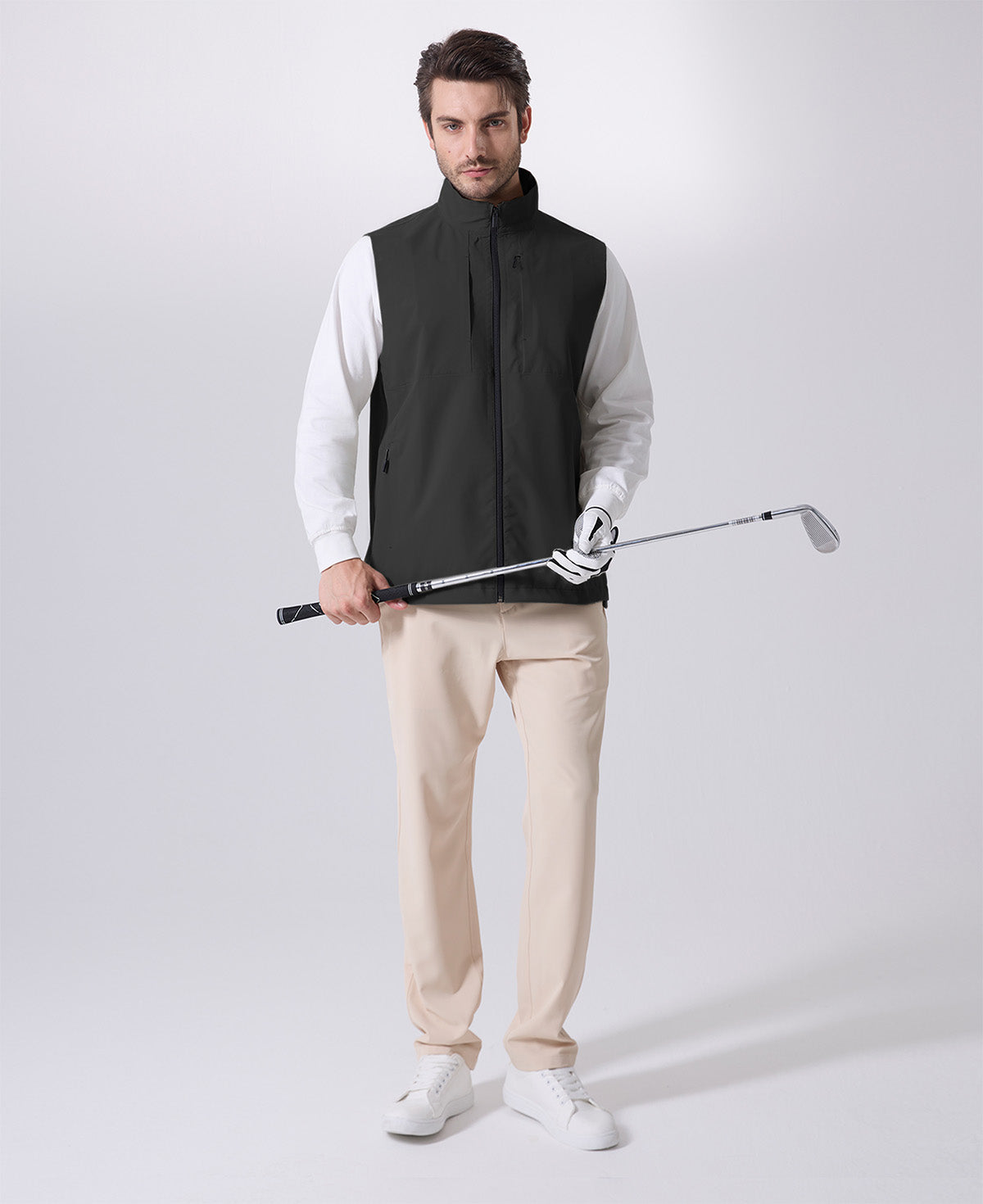 Model wearing black Men's Softshell Vest with golf club, ideal lightweight layer for outdoor leisure activities.