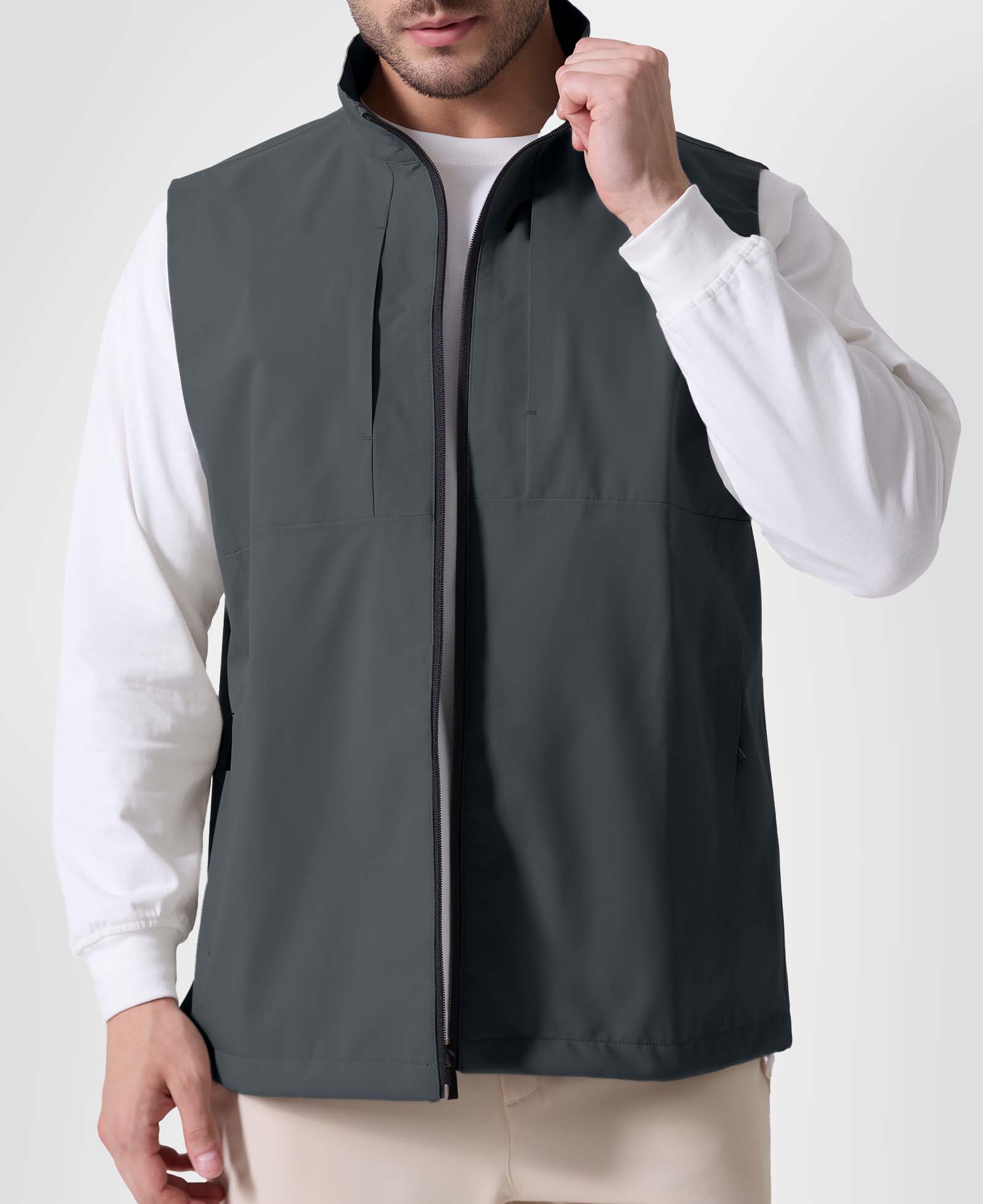 Man in dark grey Men's Softshell Vest ¨C Lightweight Windproof Sleeveless, white long-sleeve tee & khaki pants, casual layered look.