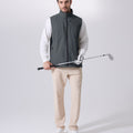 Model wearing dark grey Men's Softshell Vest with golf club, ideal lightweight layer for outdoor leisure activities.