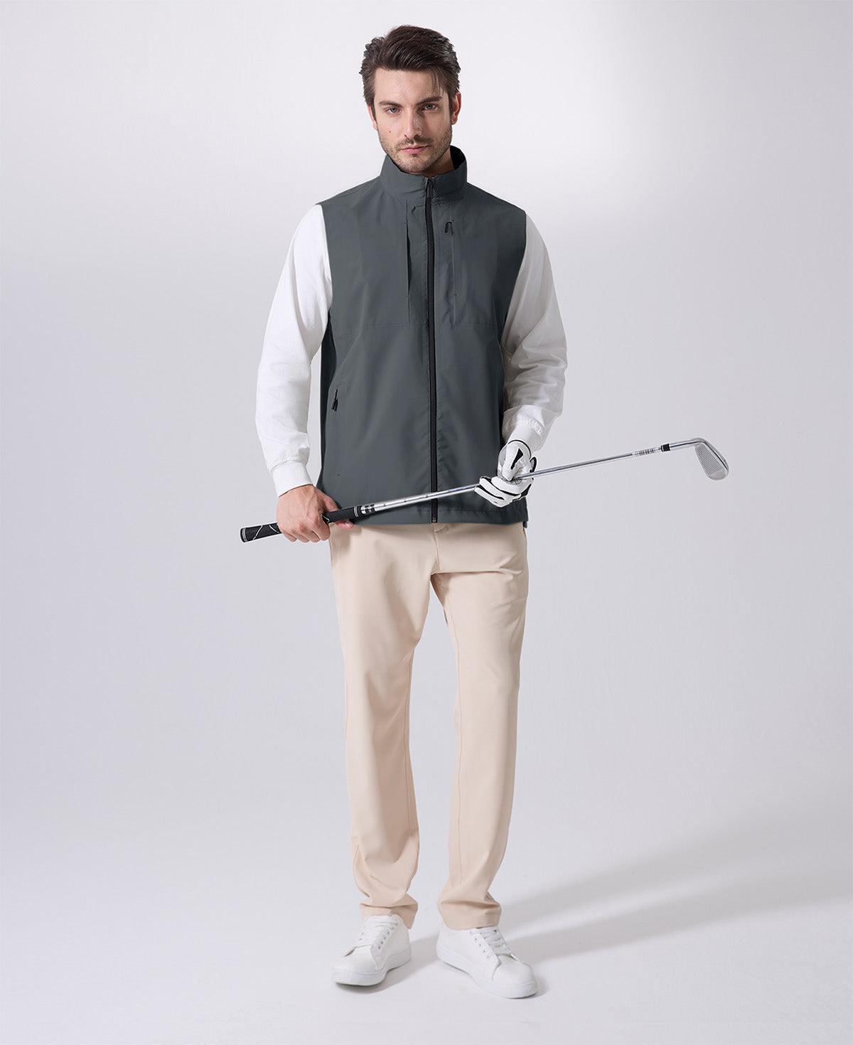 Model wearing dark grey Men's Softshell Vest with golf club, ideal lightweight layer for outdoor leisure activities.
