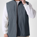 Man in light grey Men's Softshell Vest ¨C Lightweight Windproof Sleeveless, white long-sleeve tee & khaki pants, casual layered look.