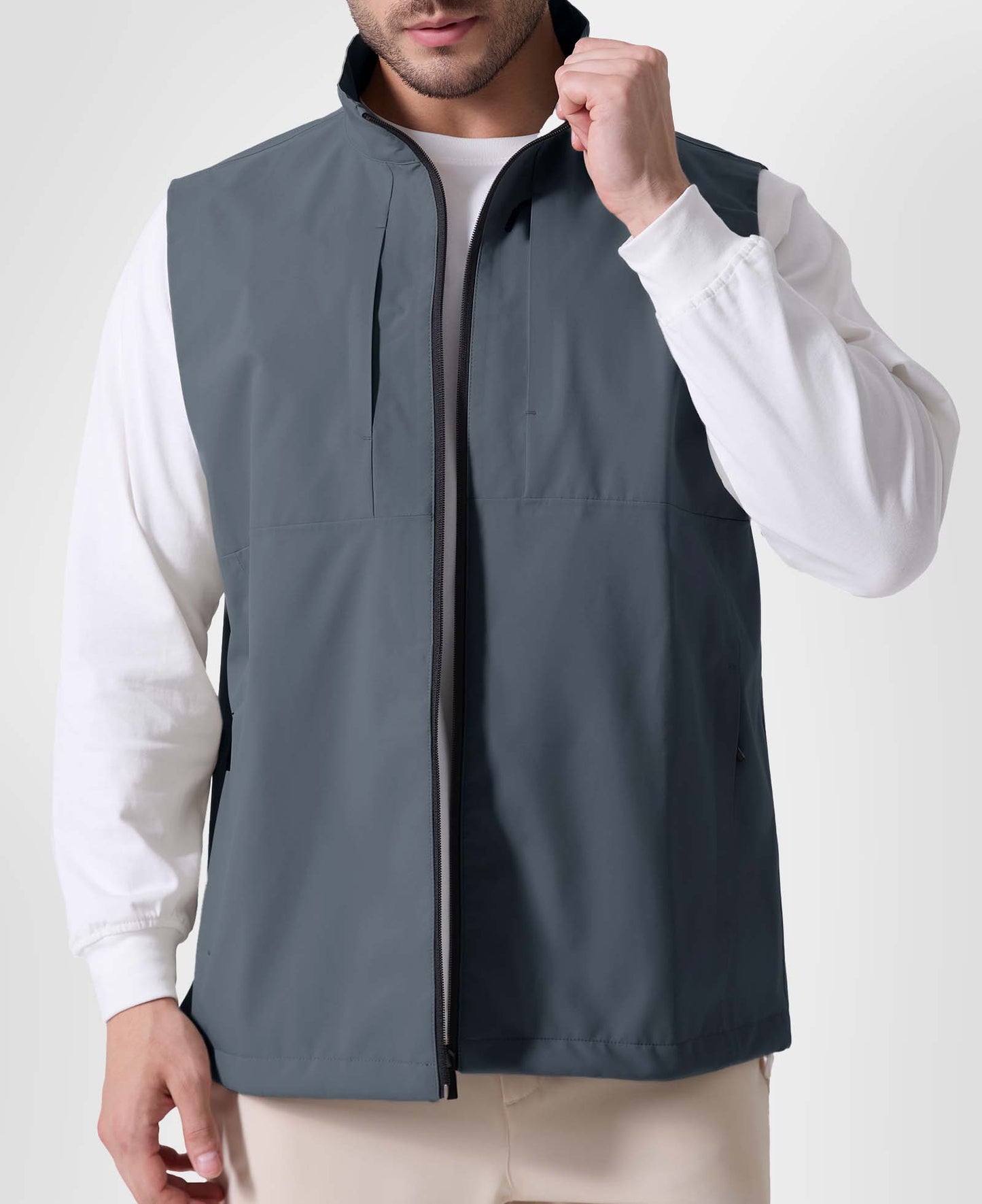 Man in light grey Men's Softshell Vest ¨C Lightweight Windproof Sleeveless, white long-sleeve tee & khaki pants, casual layered look.