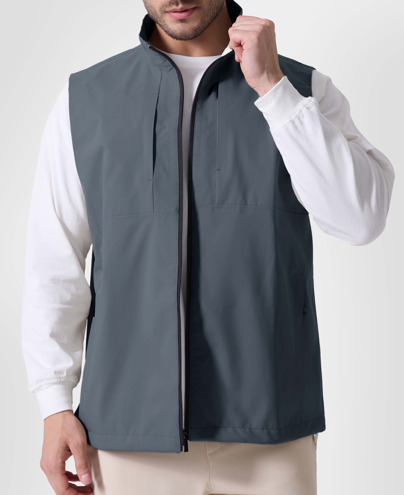Man in light grey Men's Softshell Vest ¨C Lightweight Windproof Sleeveless, white long-sleeve tee & khaki pants, casual layered look.