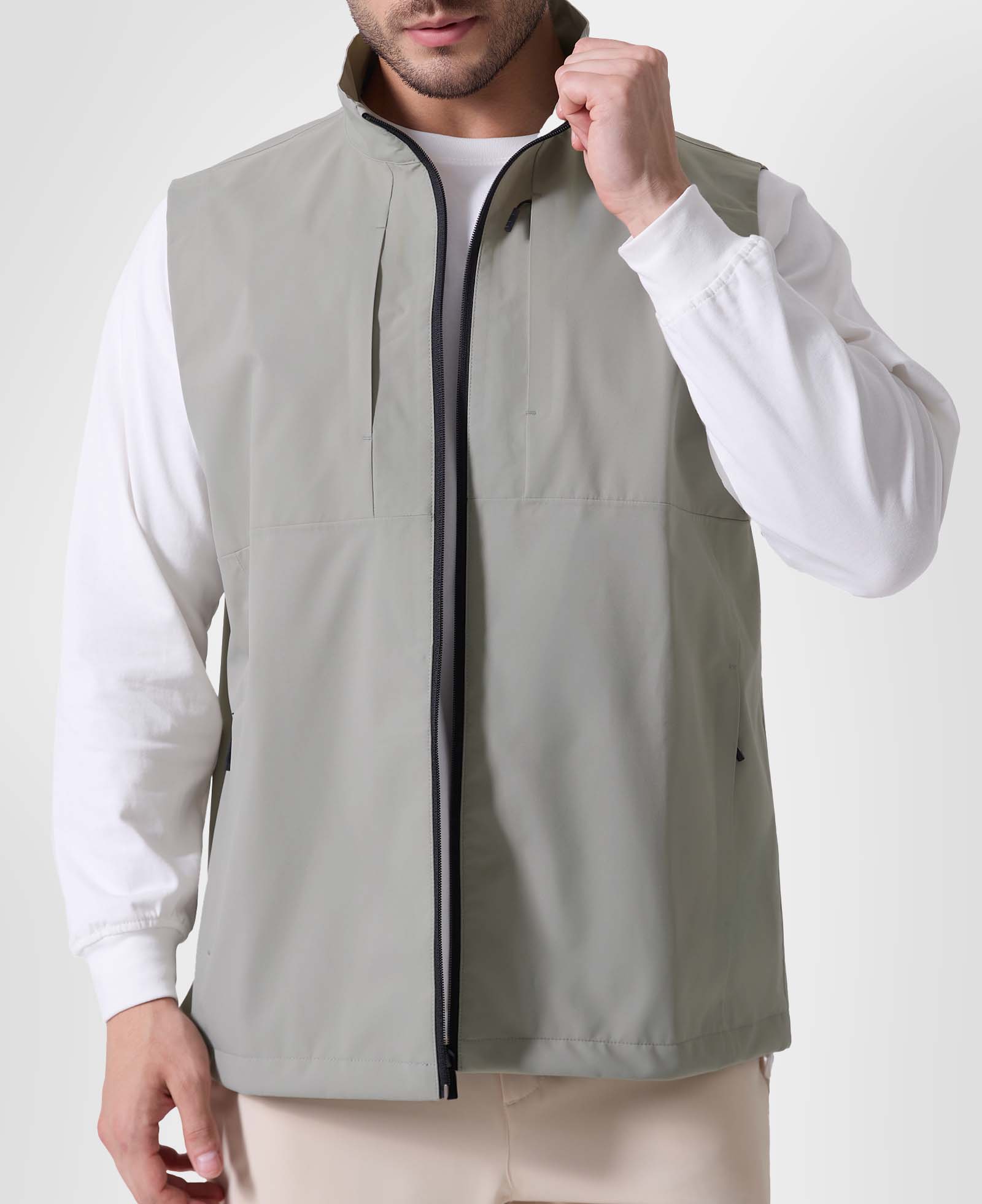 Man in sage green Men's Softshell Vest ¨C Lightweight Windproof Sleeveless, white long-sleeve tee & khaki pants, casual layered look.