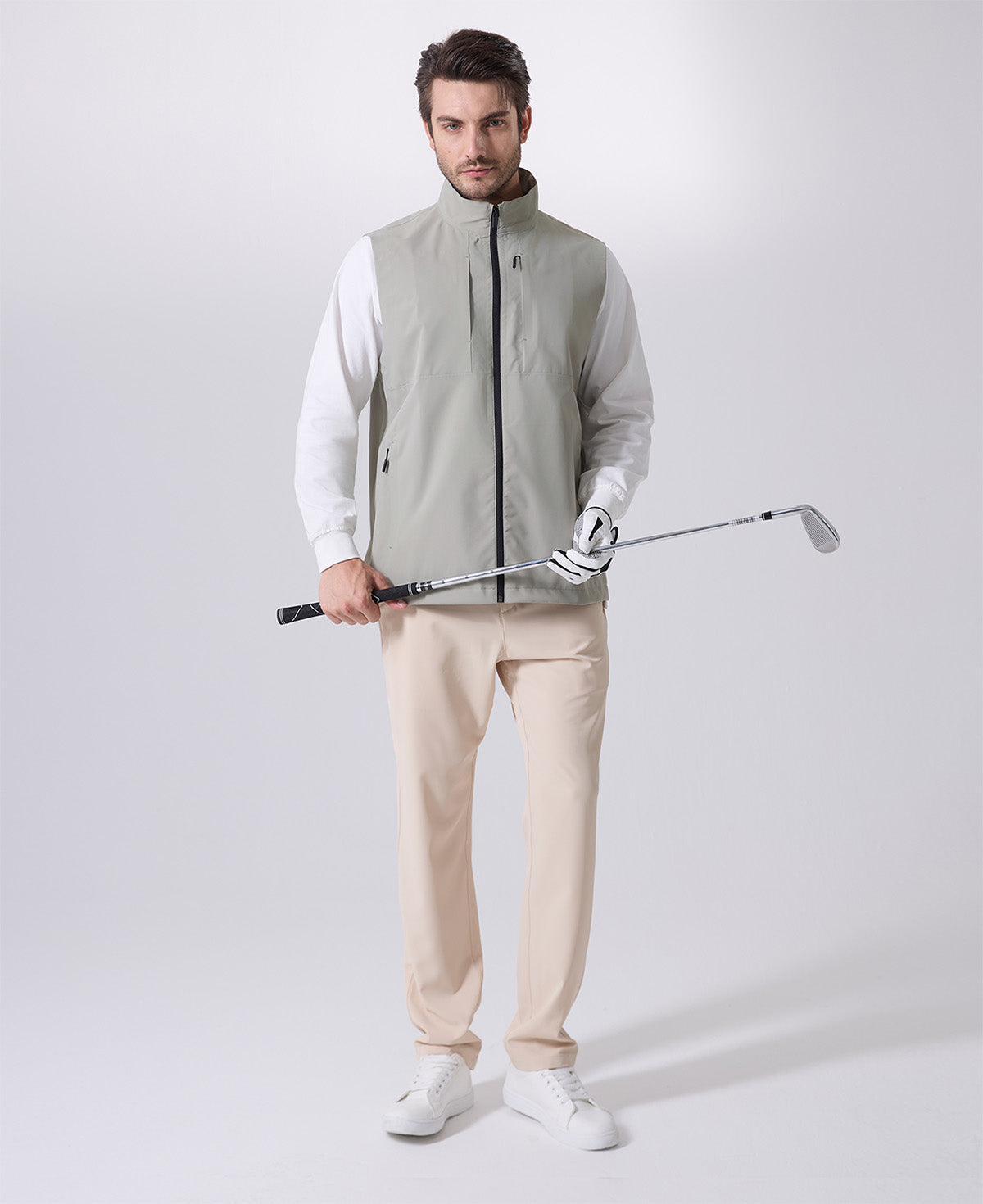 Model wearing sage green Men's Softshell Vest with golf club, ideal lightweight layer for outdoor leisure activities.