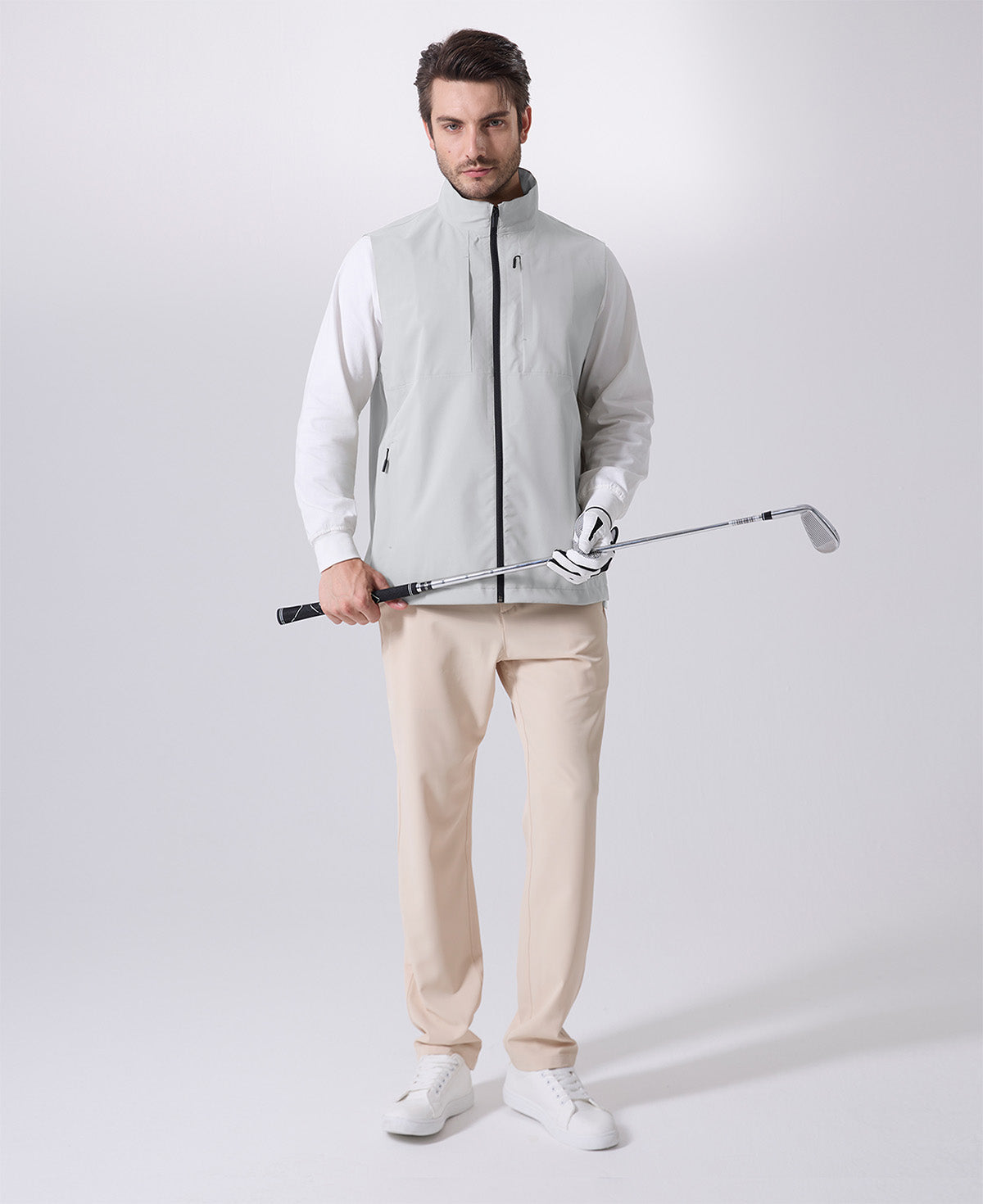 Model wearing white grey Men's Softshell Vest with golf club, ideal lightweight layer for outdoor leisure activities.