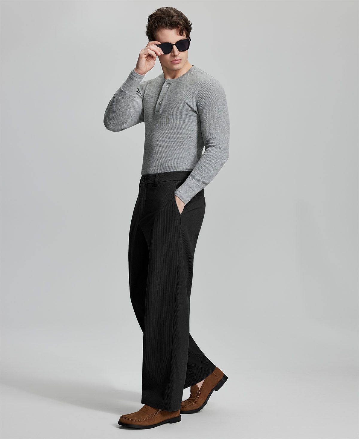 Side view of model wearing sunglasses with black wide-leg corduroy pants, highlighting loose fit and style adaptability.