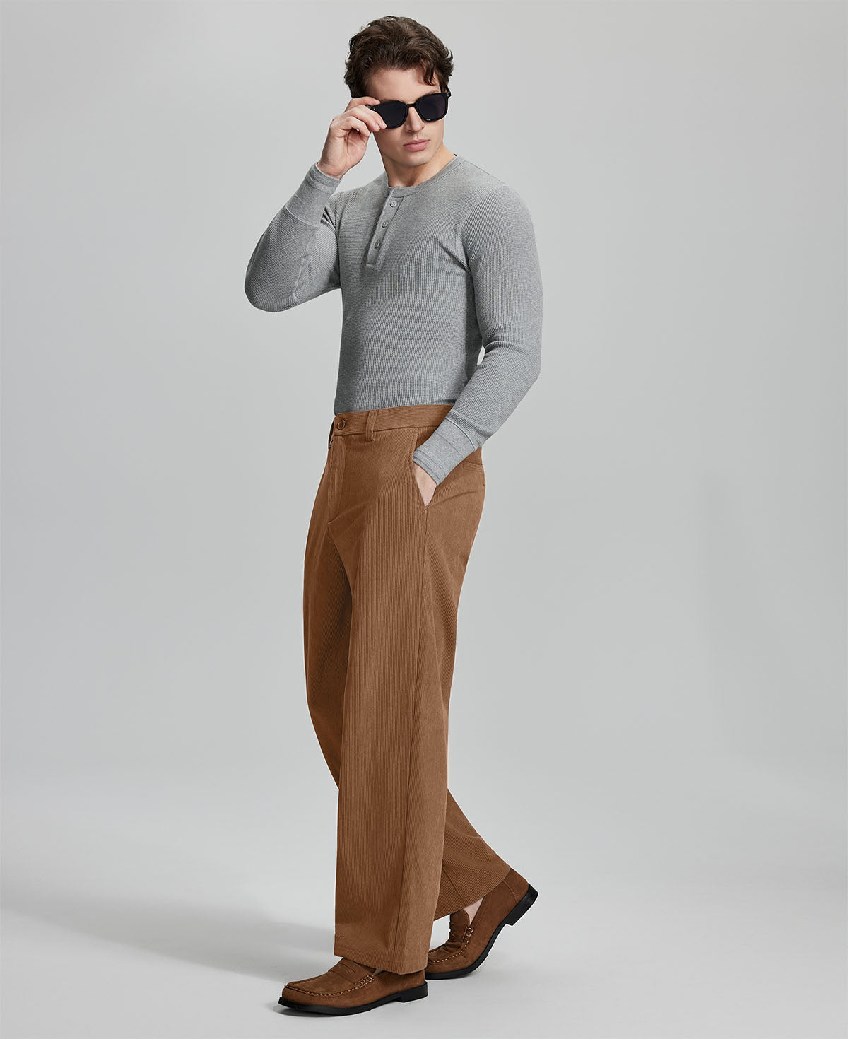 Side view of model wearing sunglasses with brown wide-leg corduroy pants, highlighting loose fit and style adaptability.
