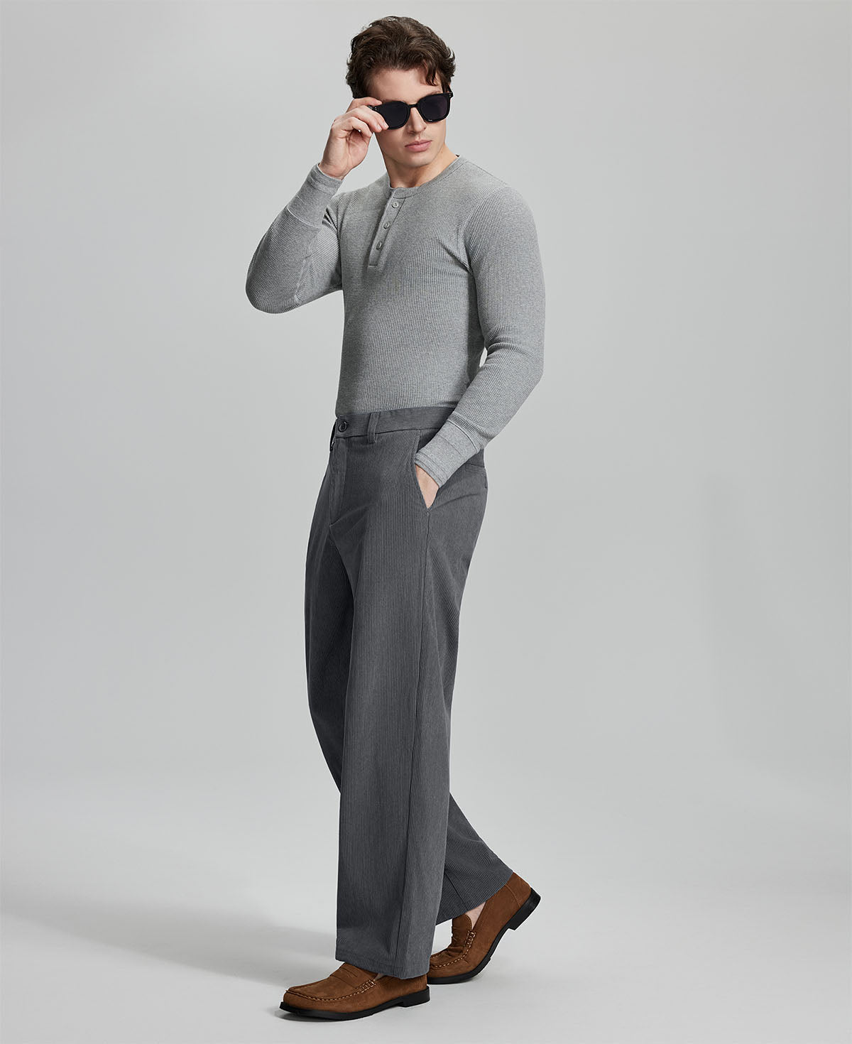 Side view of model wearing sunglasses with dark grey wide-leg corduroy pants, highlighting loose fit and style adaptability.
