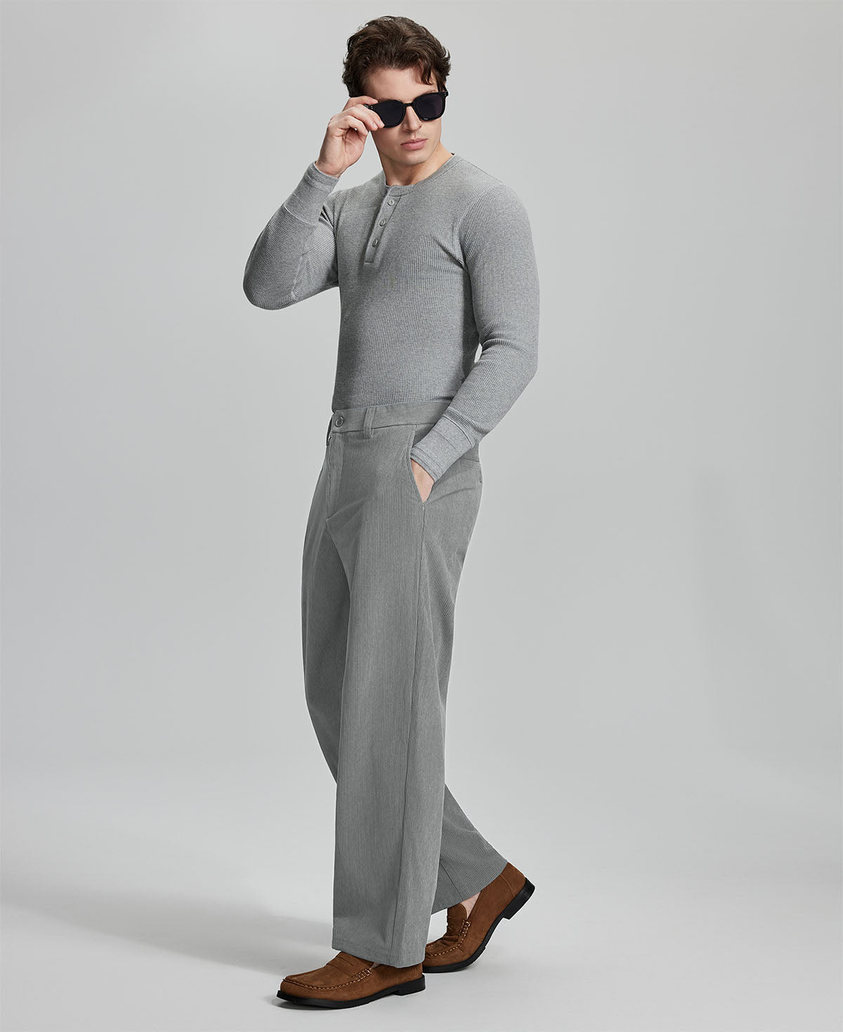 Side view of model wearing sunglasses with light grey wide-leg corduroy pants, highlighting loose fit and style adaptability.