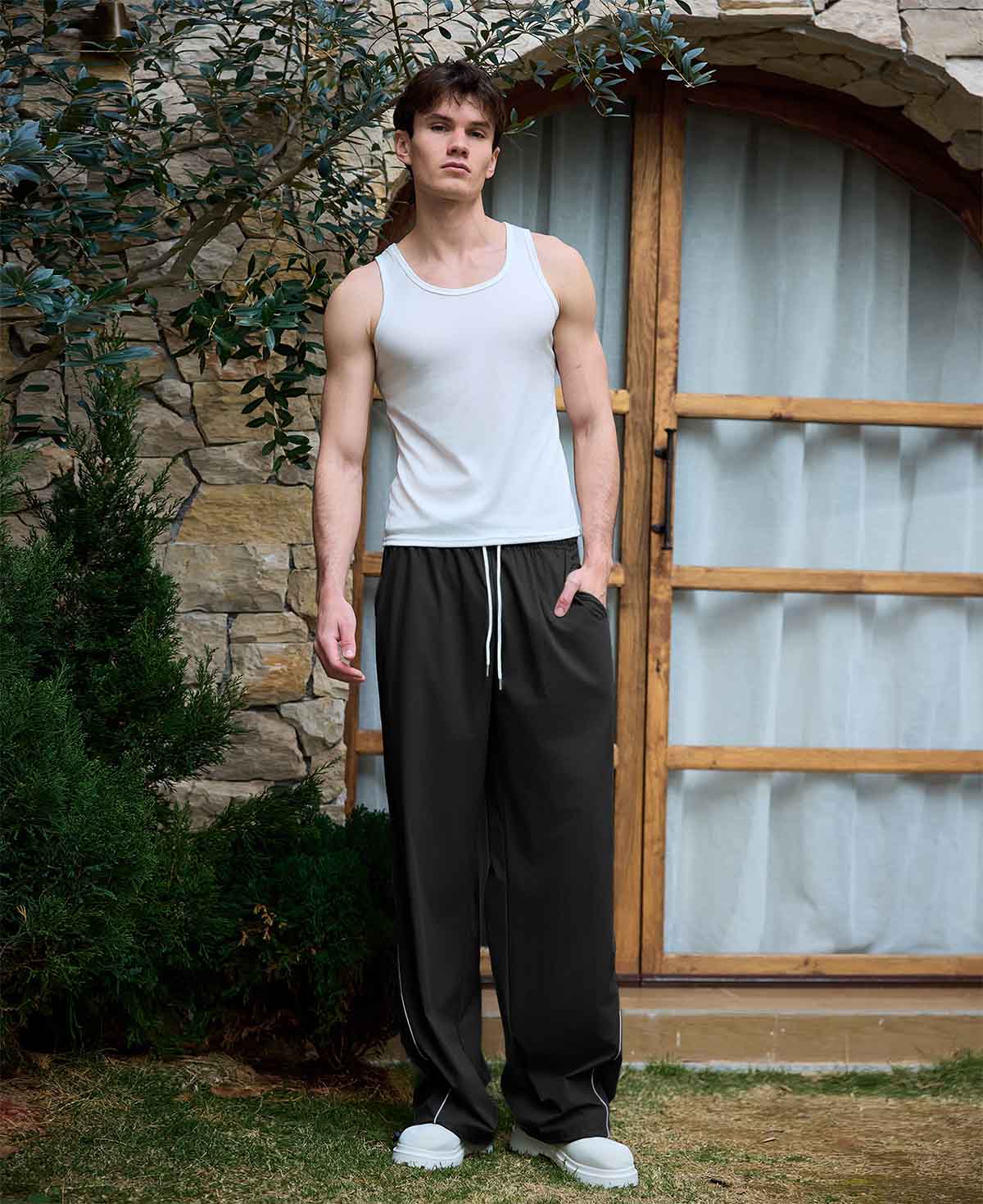 Full view of man wearing black baggy wide leg sweatpants, white sneakers, front stance, showing overall look.
