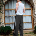 Man in black baggy wide leg sweatpants, white thick-soled shoes, back to camera, side stance on grass, showing loose fit and stripes.
