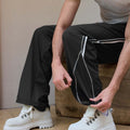 Adjustable drawstring at the hem of black baggy wide leg sweatpants, showing stitching details and fabric texture.