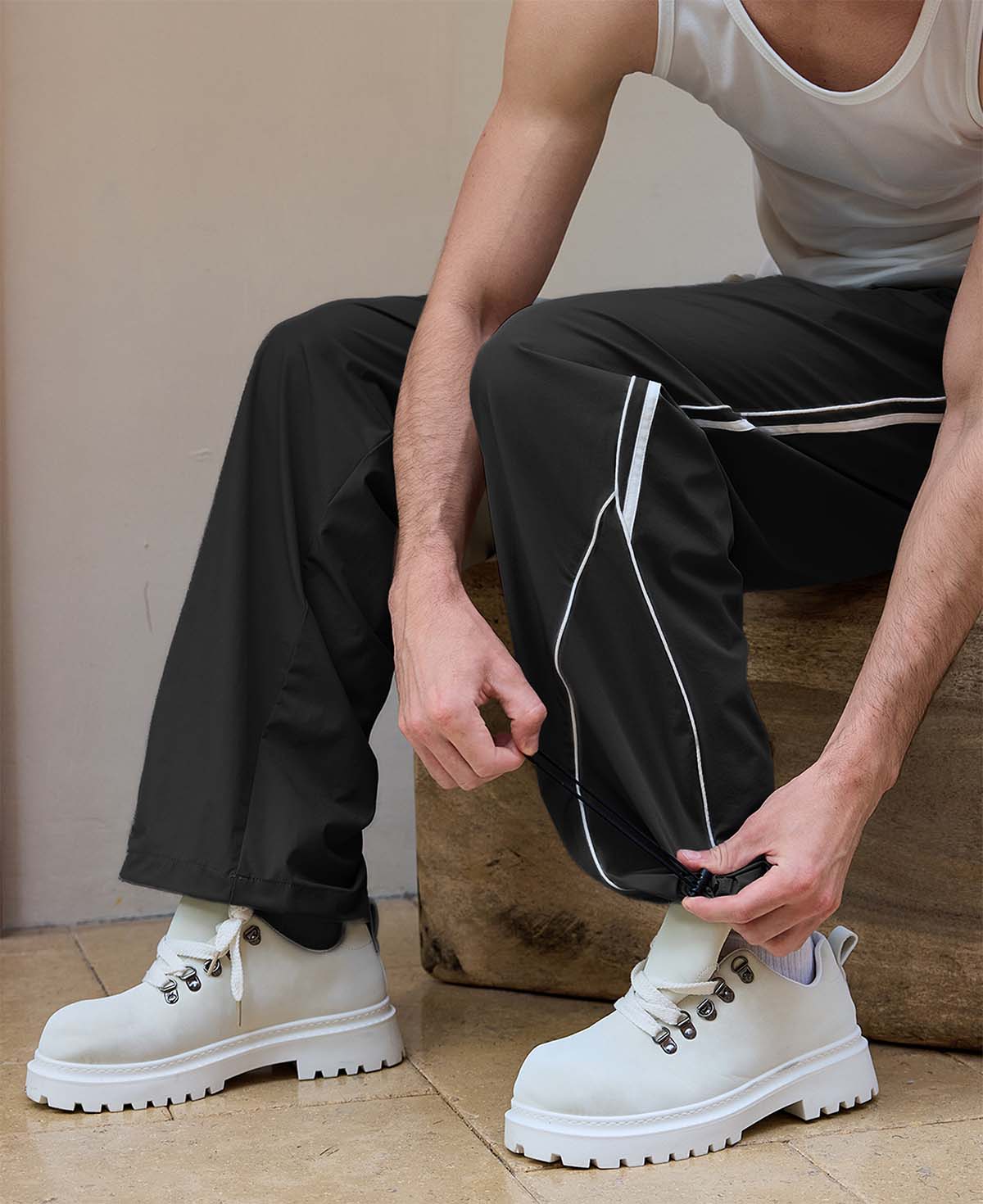 Adjustable drawstring at the hem of black baggy wide leg sweatpants, showing stitching details and fabric texture.