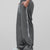 Man in dark grey baggy wide leg sweatpants, side view, showing stripe detail and loose fit. White sneakers.