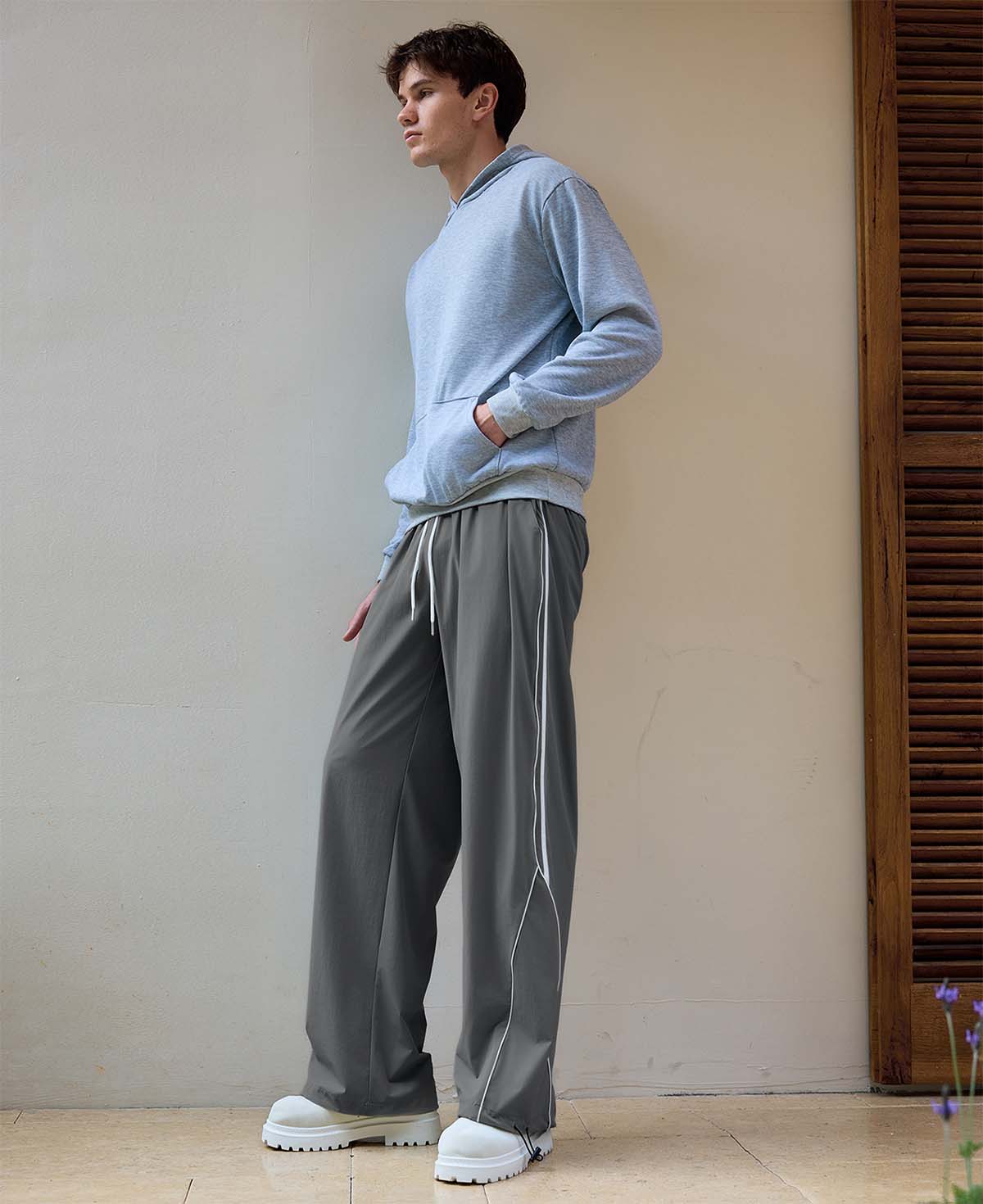 Man in dark grey baggy wide leg sweatpants, showing both side and front views while standing.