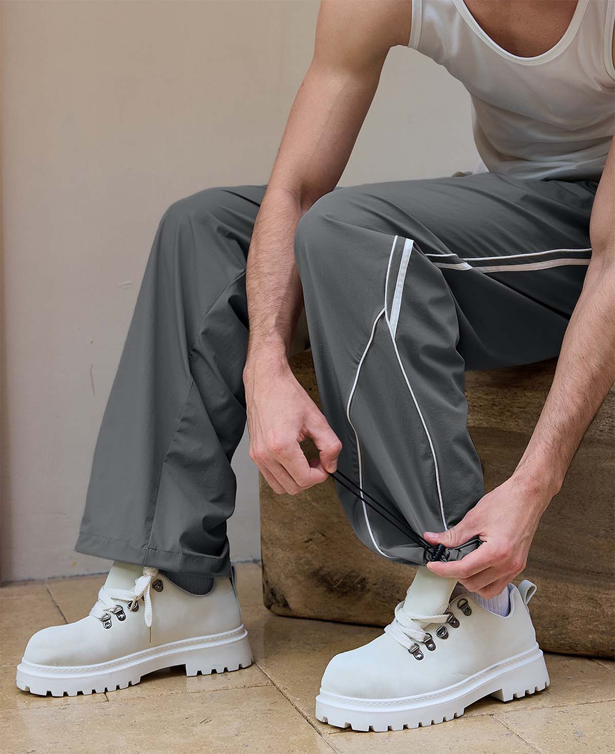 Adjustable drawstring at the hem of dark grey baggy wide leg sweatpants, showing stitching details and fabric texture.