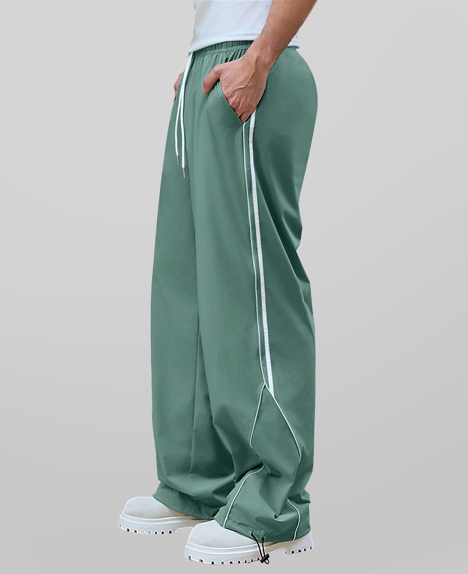 Man in green baggy wide leg sweatpants, side view, showing stripe detail and loose fit. White sneakers.