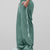 Man in green baggy wide leg sweatpants, side view, showing stripe detail and loose fit. White sneakers.