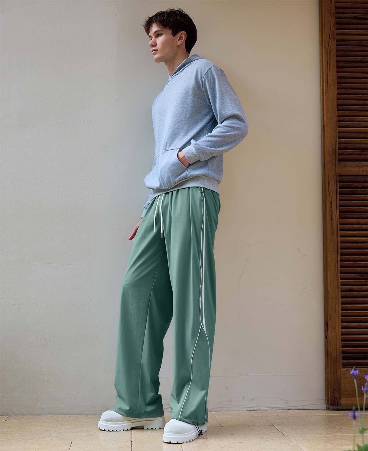 Man in green baggy wide leg sweatpants, showing both side and front views while standing.