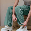 Adjustable drawstring at the hem of green baggy wide leg sweatpants, showing stitching details and fabric texture.