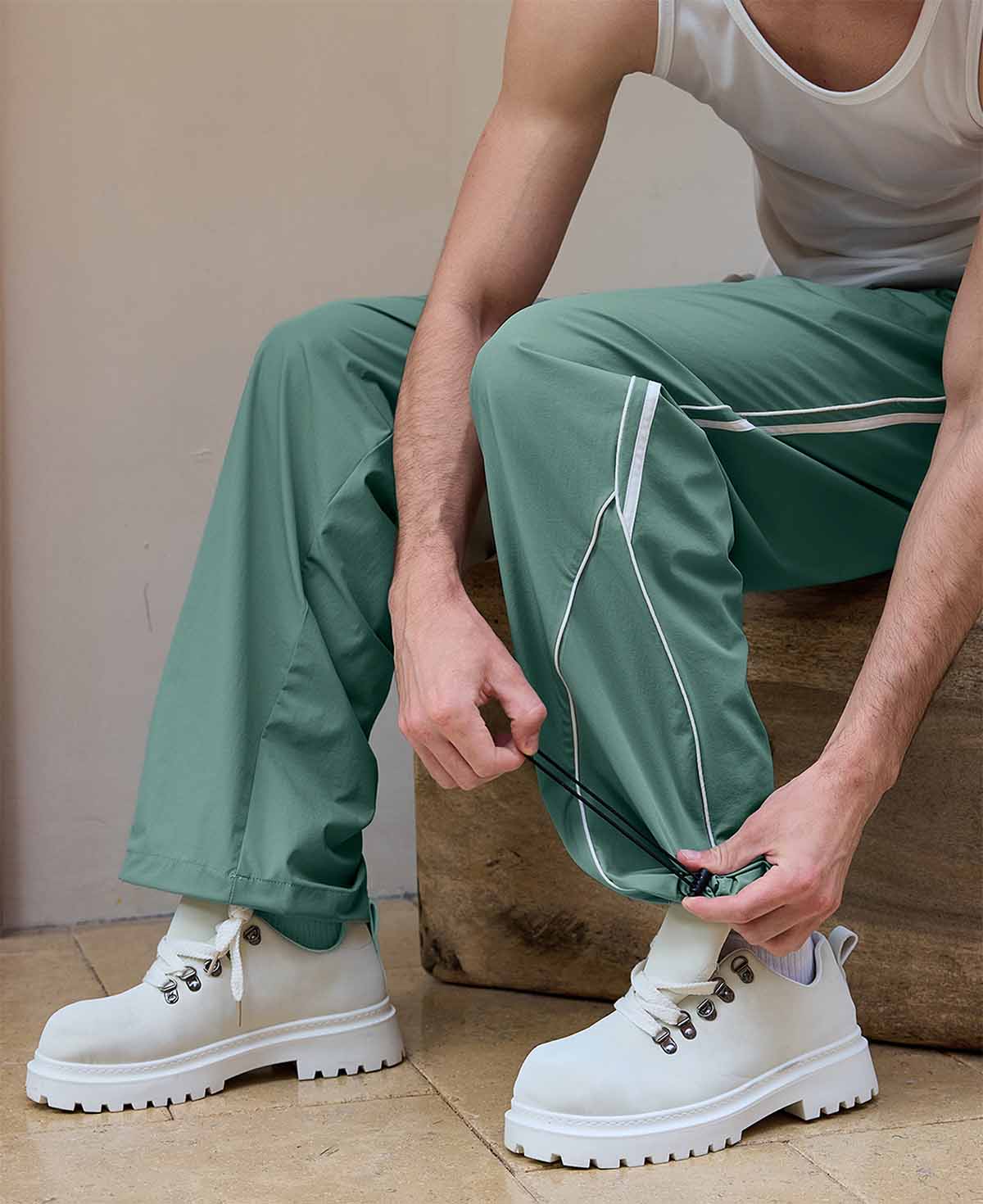 Adjustable drawstring at the hem of green baggy wide leg sweatpants, showing stitching details and fabric texture.