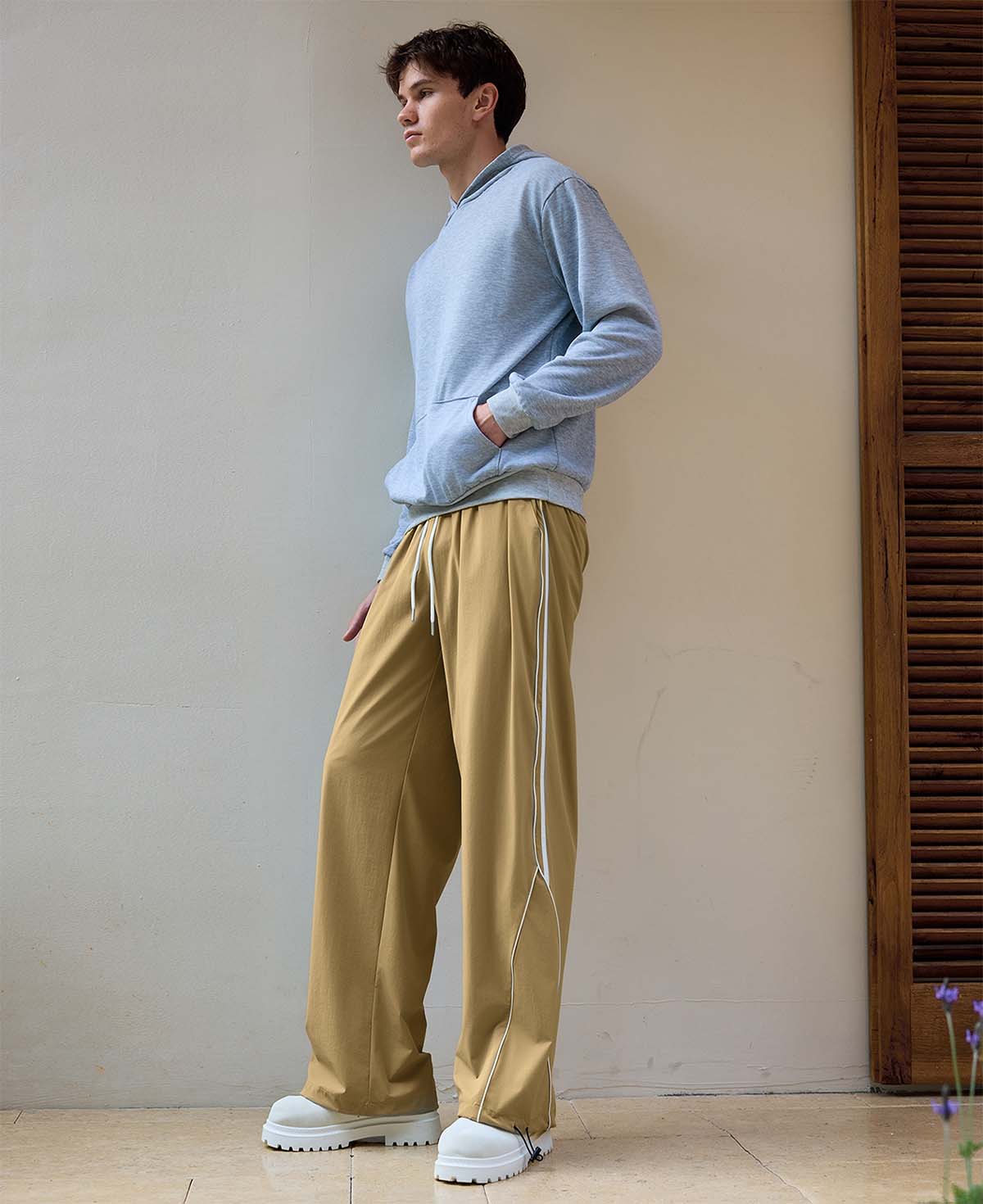 Man in khaki baggy wide leg sweatpants, showing both side and front views while standing.