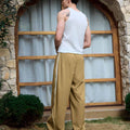Man in khaki baggy wide leg sweatpants, white thick-soled shoes, back to camera, side stance on grass, showing loose fit and stripes.