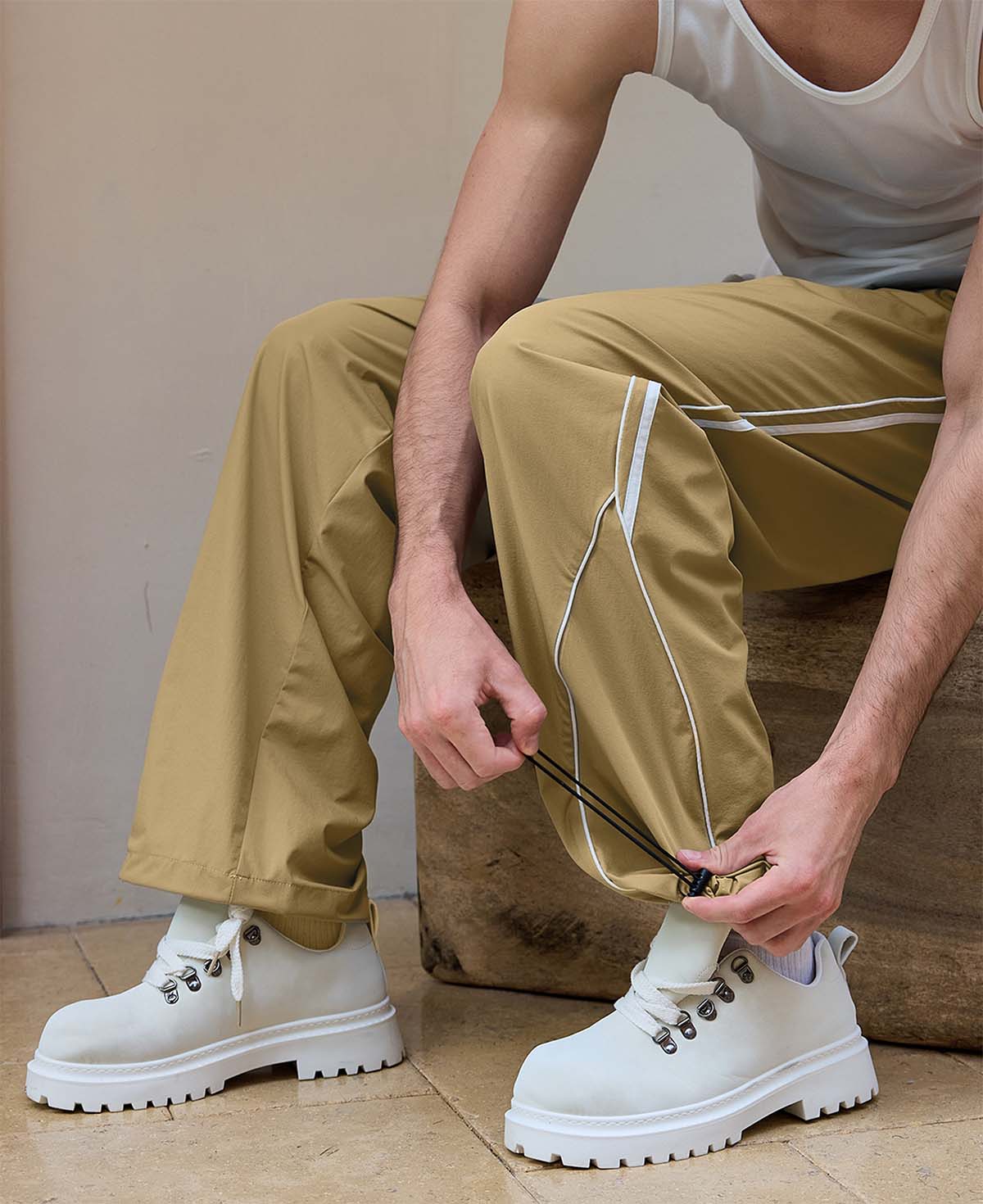 Adjustable drawstring at the hem of khaki baggy wide leg sweatpants, showing stitching details and fabric texture.